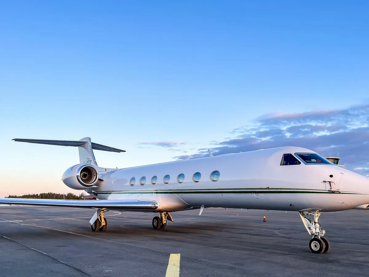 Large business jet parked on a sunny ramp under a blue sky
